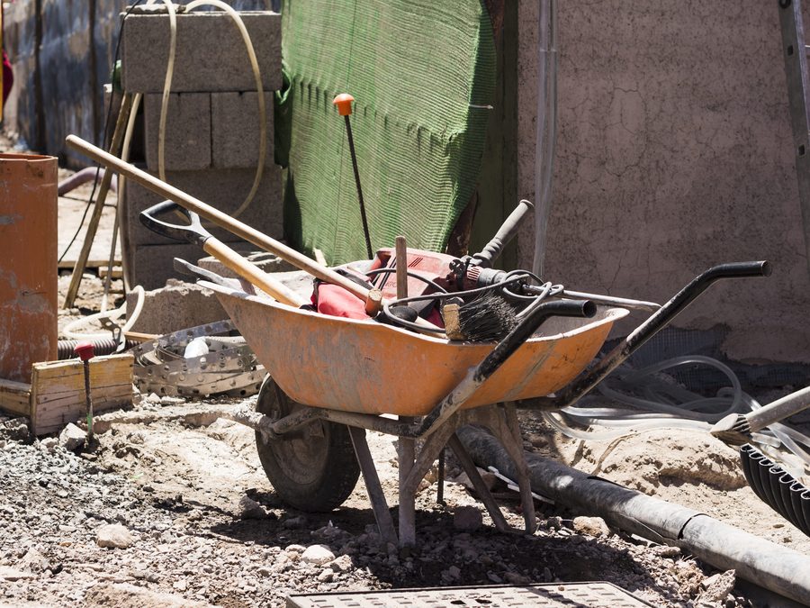 A wheelbarrow loaded with tools and rubble on a building site